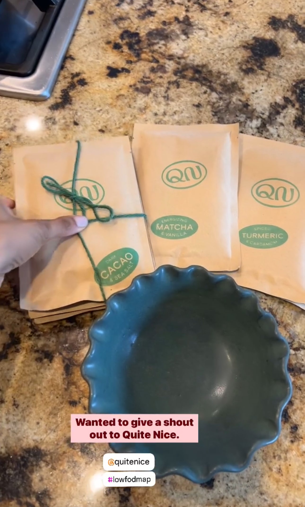 A hand is holding a bundle of three brown paper packages labeled Cacao, Matcha, and Turmeric, next to a green scalloped bowl. A sticker reads, Wanted to give a shout out to Quite Nice. Tags: @quitenice and #lowfodmap.