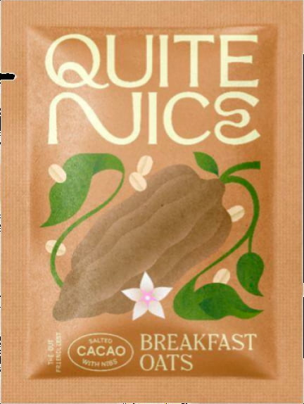 A brown packet labeled Quite Nice Breakfast Oat Mix features a large cacao pod illustration with green leaves and a small white flower. Text reads The Gut Friendly Test, highlighting real food ingredients with rich cacao & sea salt for improved gut health.