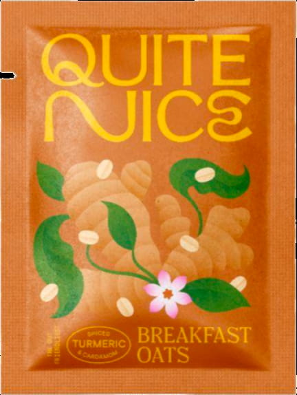 The image displays a packet labeled Quite Nice Spiced Breakfast Oats, boasting real food ingredients with turmeric and cardamom flavors. The orange packaging features illustrations of turmeric roots, green leaves, and a pink flower, promoting fiber and gut health benefits.